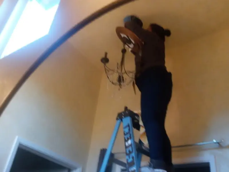 Electrician installing a chandelier in a Westmoreland residence